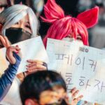 Riven and Ahri cosplayers holding signs at MSI 2022